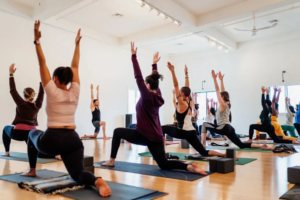 Instructor demonstrating yoga pose with students in free class– digital marketing strategies for a yoga studio